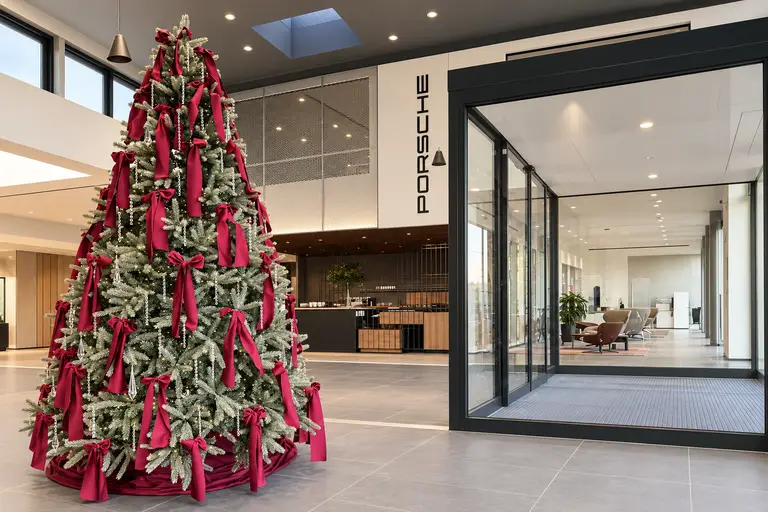 Albero di Natale con fiocchi bordeaux e pendenti di cristallo all'ingresso di uno showroom auto